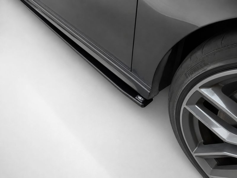K187-002_4jpg - OPSHOLDERS Close-up of a dark gray car's lower side and wheel, showing a large alloy rim and a Pirelli tire; a small 4WD badge is visible on the side skirt