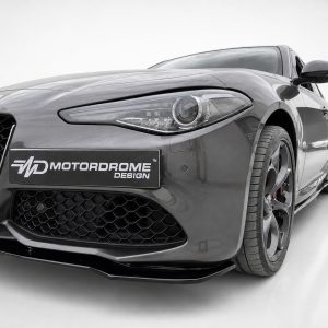 Front-left close-up of a gray Alfa Romeo sports car with a Motordrome Design plate on the bumper to the left.