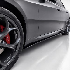 Close-up of a dark gray sports car's front wheel, showing a red brake caliper and multi‑spoke alloy rim. The car body and door panel are reflected on the side.