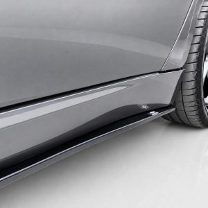 Close-up of a gray sports car's side panel, showing the lower body line and alloy wheel with tire.