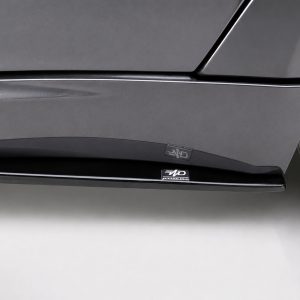 Close-up of a dark gray car's lower side panel with glossy trim and a small 'MD' branding badge near the wheel.