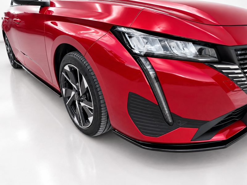 Close-up of a glossy red car's front left area, showing the headlight, grille, and alloy wheel still in view