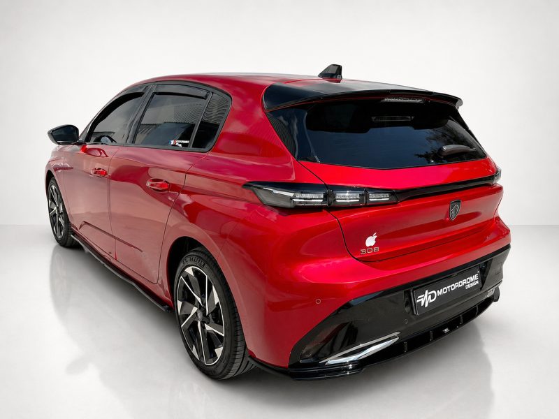 Rear three-quarter view of a glossy red hatchback with black rear window, distinctive taillights, and large multi-spoke wheels in a white studio setting