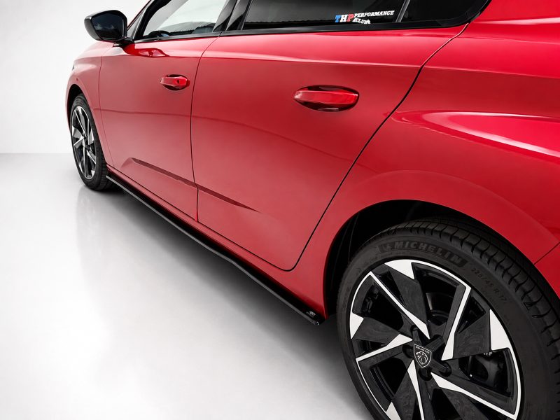 Close-up of a glossy red car door and front fender, with a large black alloy wheel visible on the right side.