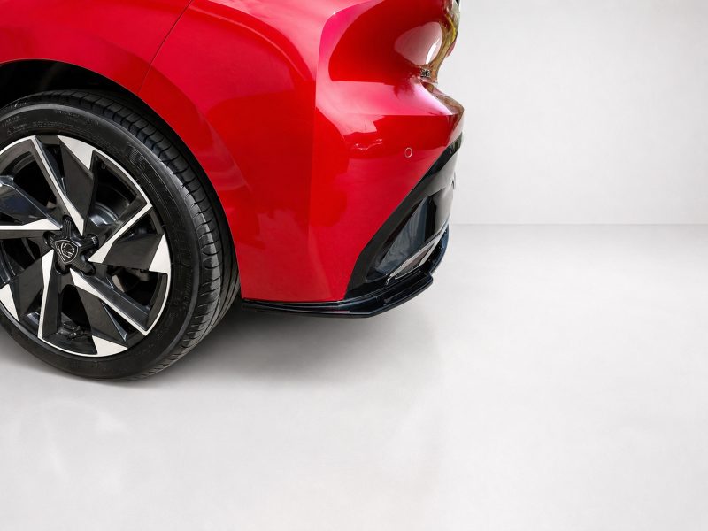 K189-003_4jpg - OPSHOLDERS Close-up of a red car's front left area showing the wheel and tire with a glossy paint finish.
