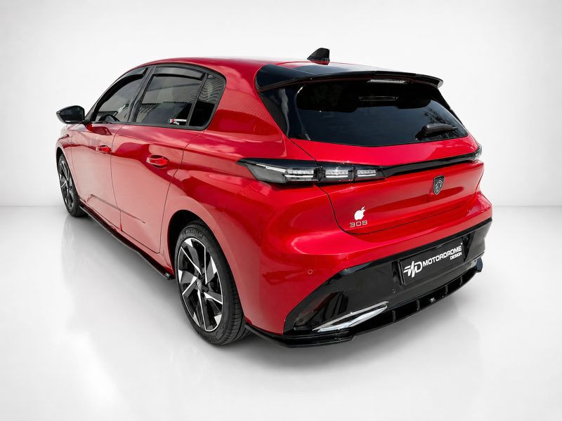 K189-003_5jpg - OPSHOLDERS Red compact hatchback photographed from a rear three-quarter angle, showing a black roof spoiler, dark rear window, and large alloy wheels in a studio setting