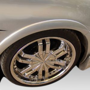 Close-up of a silver car wheel with a polished chrome multi-spoke rim and low-profile tire on a light-colored vehicle.