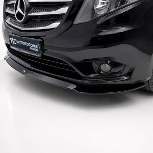 Front-left portion of a glossy black car; visible Mercedes grille, headlight, and a custom MOTORDROME DESIGN plate on the bumper.