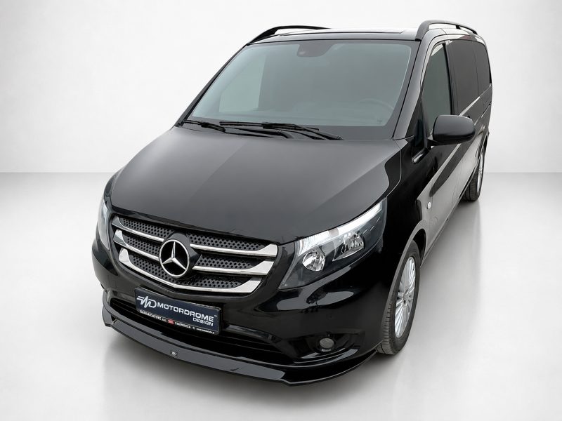 Front-left angled view of a glossy black Mercedes-Benz van, showing the grille, emblem and headlights in a studio setting.