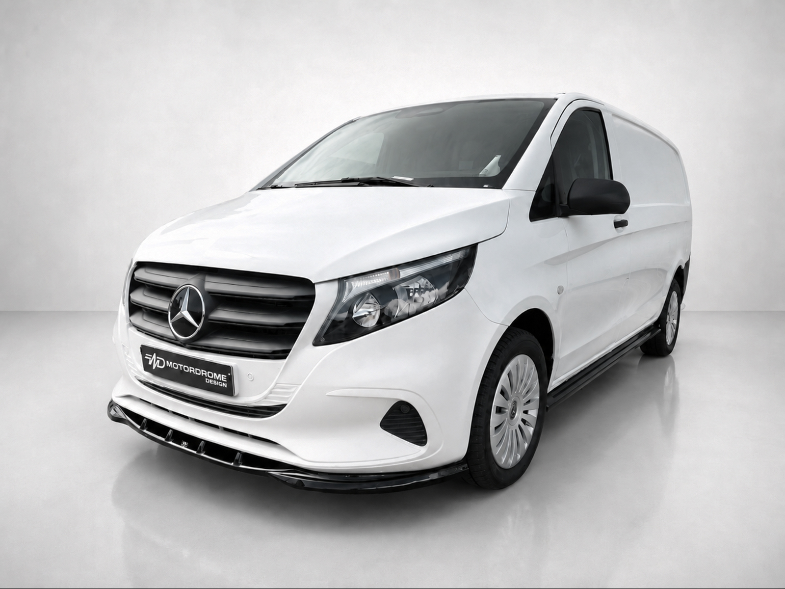 K190-002_2jpg - OPSHOLDERS Front-left view of a white Mercedes cargo van in a studio setting, showing the grille and emblem up close.