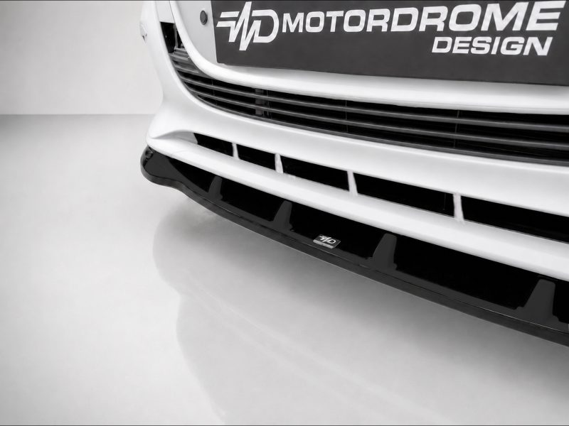 K190-002_4jpg - OPSHOLDERS Close-up of a white car front showing a black grille and 'Motordrome Design' branding plate on the bumper.