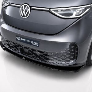 Close-up of a dark grey Volkswagen car front with logo, sleek headlight strip, and a honeycomb grille; license plate reads 'Motordrome Design'.