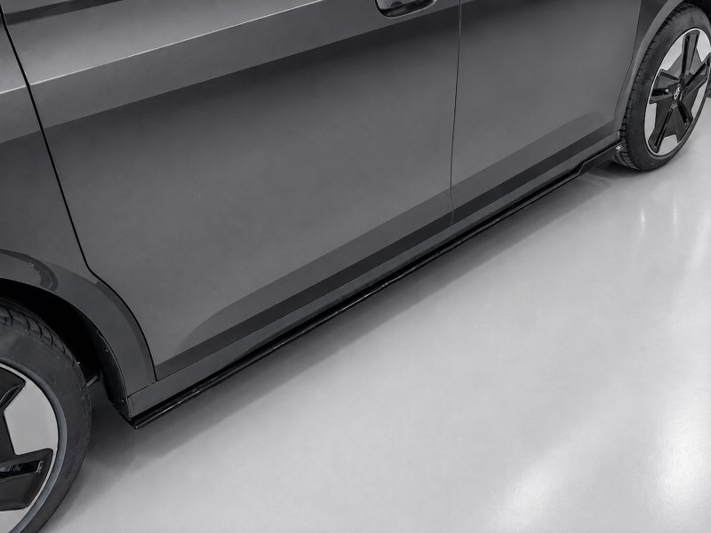 Close-up of a dark gray car’s side, showing the rocker panel and a wheel with alloy rim
