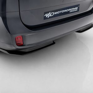 Rear view of a dark gray van with a Motordrome Design logo on the bumper and a red taillight visible