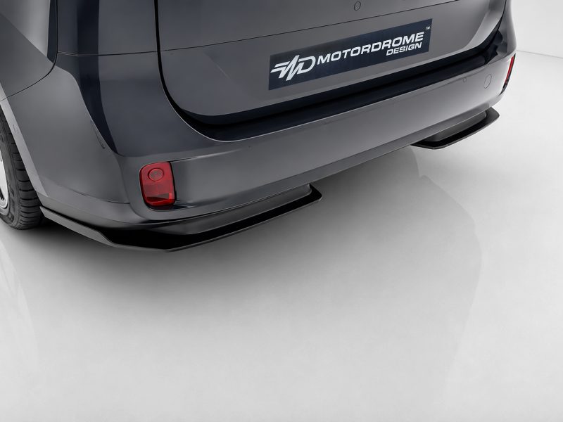 Rear view of a dark gray van with a Motordrome Design logo on the bumper and a red taillight visible