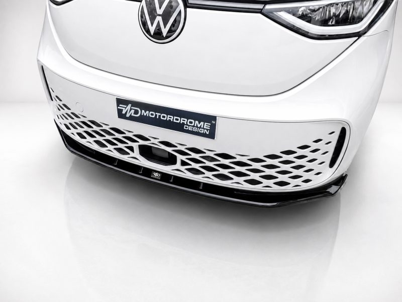Front view of a white car’s grille with a Volkswagen emblem and a mesh lower grille reading 'MOTORDROME DESIGN' on a dark plate