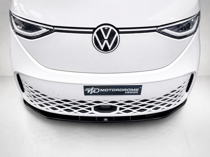 Front view of a white Volkswagen car highlighting the VW emblem and a lattice-style lower grille with a MotorDrome Design plate beneath it