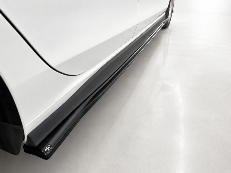K192-002_4jpg - OPSHOLDERS Close-up of a white car's side with a black running board and a small logo at the bottom edge.