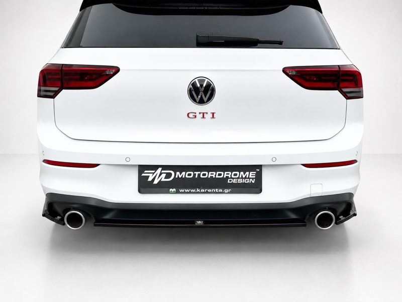 K192-003_4jpg - OPSHOLDERS Rear view of a white Volkswagen with a central GTI badge, VW emblem, red tail lights, and a Motordrome Design license plate including karenta.gr URL.