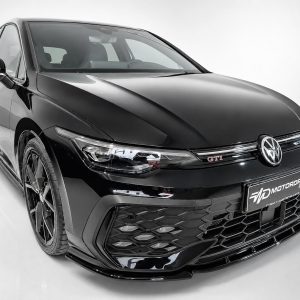 Front-left view of a glossy black Volkswagen GTI in a studio, showcasing its aggressive grille and LED headlights.