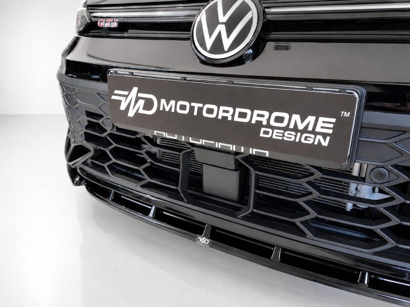 Front view of a black Volkswagen with the VW emblem and a Motordrome Design license plate.