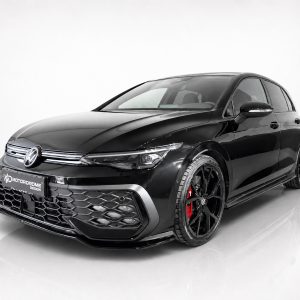 Black Volkswagen hatchback in a studio, shown from the front three-quarter angle with large black wheels and red brake calipers to suggest performance styling.