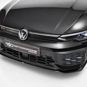 Front view of a glossy black Volkswagen with GTI badge and illuminated headlights on the right side.