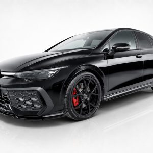 Front three-quarter view of a glossy black Volkswagen sports sedan with large black wheels and red brake calipers, on a white studio backdrop.
