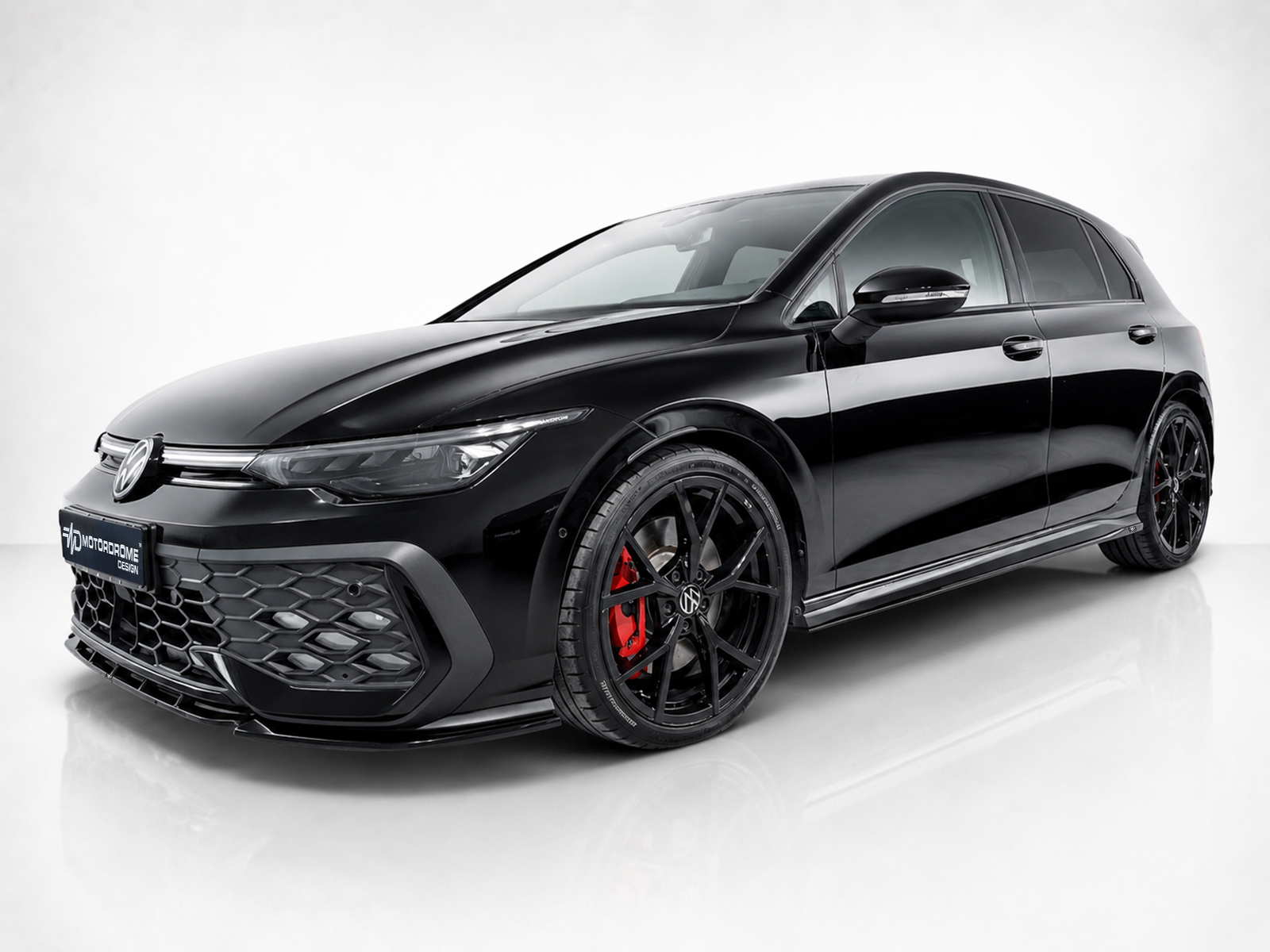 K192-007_1jpg - OPSHOLDERS Front three-quarter view of a glossy black Volkswagen sports sedan with large black wheels and red brake calipers, on a white studio backdrop.