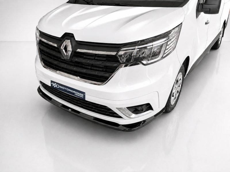 Front three-quarter view of a white Renault van showing the grille, emblem, and headlights in a studio setting, with a Motordrome Design plate on the bumper.