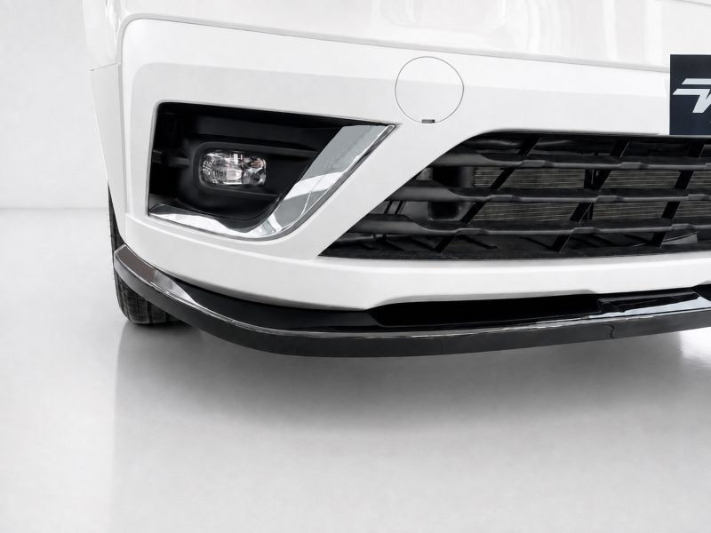 Close-up of the front left corner of a white car, showing the headlight, grille, and lower bumper lip on a clean surface.