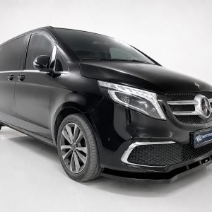 Front three-quarter view of a glossy black Mercedes-Benz van in a studio setting with a chrome grille and large emblem