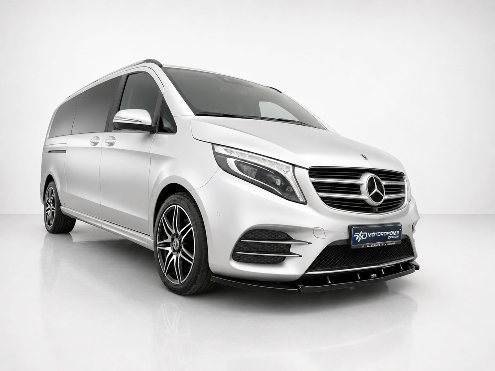 K195-002_2jpg - OPSHOLDERS White Mercedes van shown from the front-right in a studio, with a prominent emblem and alloy wheels central to the image.