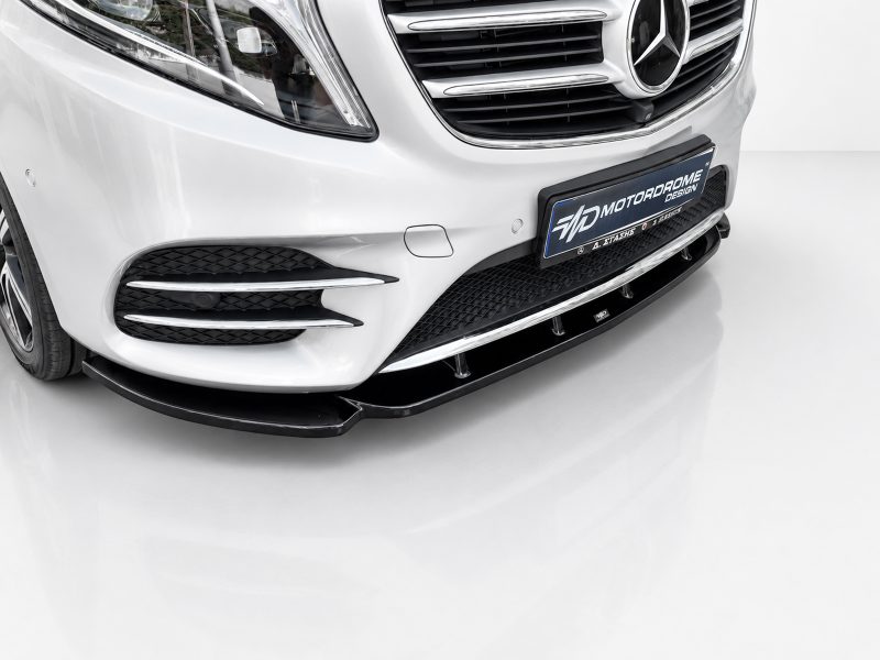 K195-002_3jpg - OPSHOLDERS Front of a white luxury car showing the grille, headlight, and a black front lip spoiler with a dealership plate reading MOTORADOME DESIGN