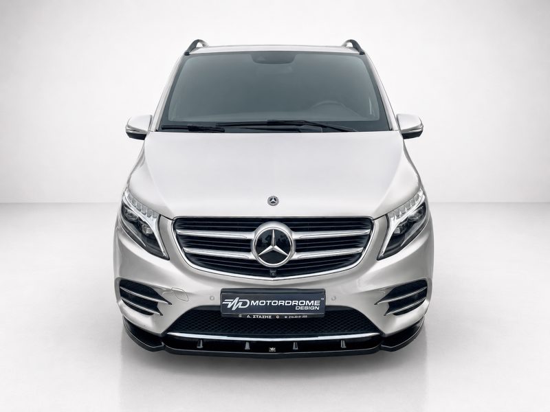 K195-002_4jpg - OPSHOLDERS Front view of a silver Mercedes-Benz SUV in a bright studio, showcasing the chrome grille and emblem.
