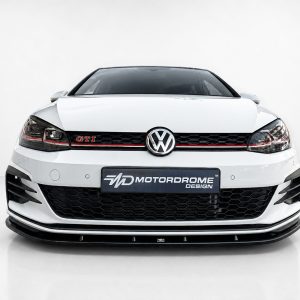 Front view of a white Volkswagen GTI with red accent stripe and Motordrome Design license plate in a studio setting