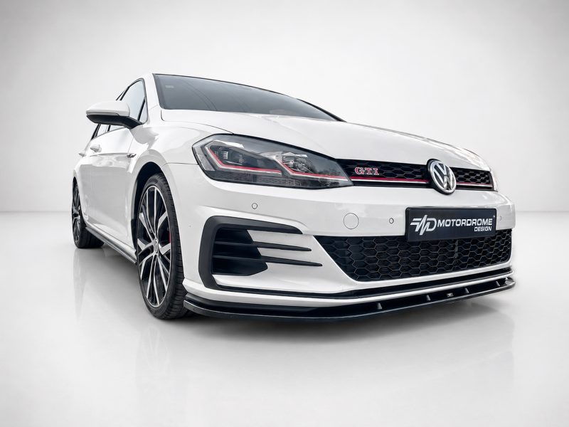 White Volkswagen GTI in a three-quarter front view in a studio setting, showing the honeycomb grille and red trim detail