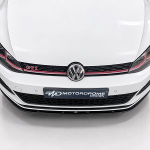 White VW GTI car front view with emblem and black honeycomb grille, Motordrome Design plate visible