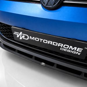 Close-up of a blue car front featuring a black license plate reading MOTORDROME DESIGN and a honeycomb grille below.