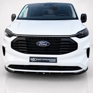 Front view of a white Ford van in a studio, showing the black grille and Ford emblem with a Motordrome Design plate on the bumper.