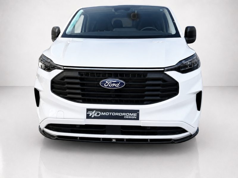 Front view of a white Ford van in a studio, showing the black grille and Ford emblem with a Motordrome Design plate on the bumper.