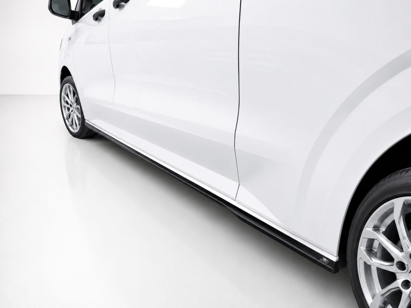 White car shown from the side, featuring doors, a black running board, and alloy wheels along the bottom edge.