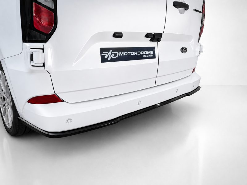 K200-003_3jpg - OPSHOLDERS White van rear with a dark logo decal reading 'MD MotorDrome Design' on the tailgate, Ford badge visible, and a black rear bumper protector edge.