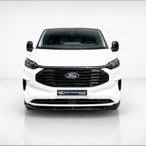 Front view of a white Ford van with a black grille and side mirrors in a studio setting.