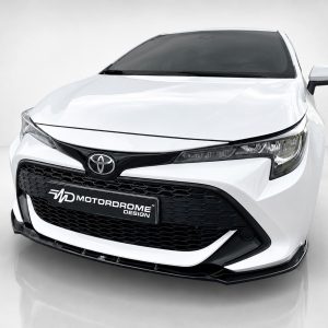Front view of a white Toyota car in a showroom, featuring a black grille and prominent emblem on the hood.