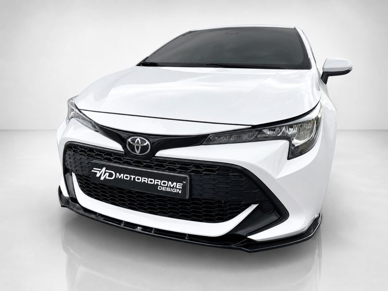 Front view of a white Toyota car in a showroom, featuring a black grille and prominent emblem on the hood.