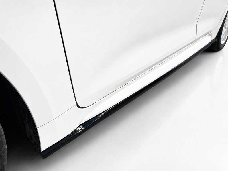 Close-up of a white SUV's lower side, showing the running board and part of the front wheel.