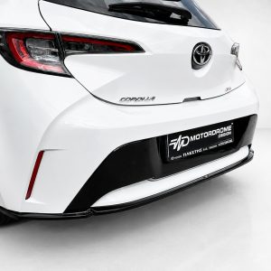 K201-003_2jpg - OPSHOLDERS White Toyota Corolla rear view with prominent taillights and a black lower bumper, license plate area labeled Motordrome Design.