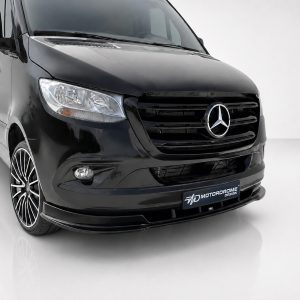Front-left three-quarter view of a glossy black Mercedes-Benz van with prominent grille and large alloy wheels in a studio setting