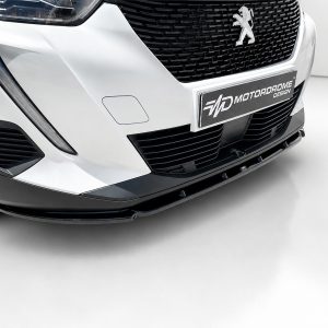Close-up of a white Peugeot front end, showing the grille, headlight, and lower bumper with a designer plate.